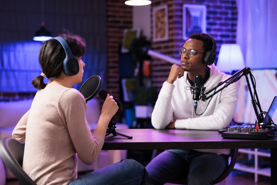 Two people recording a conversation with microphones and headphones